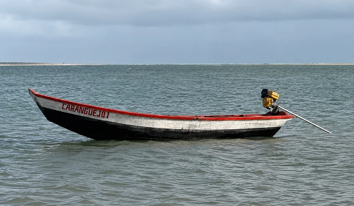 O barco Caranguejo I na água, com a outra margem do rio ao fundo