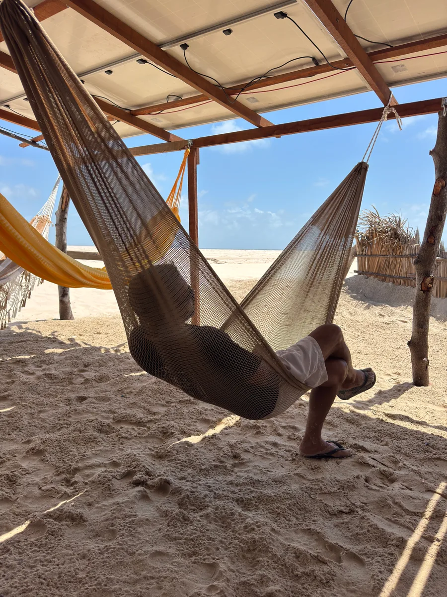 Un'amaca all'ombra della Cabana do Caranguejo, con un visitatore che riposa