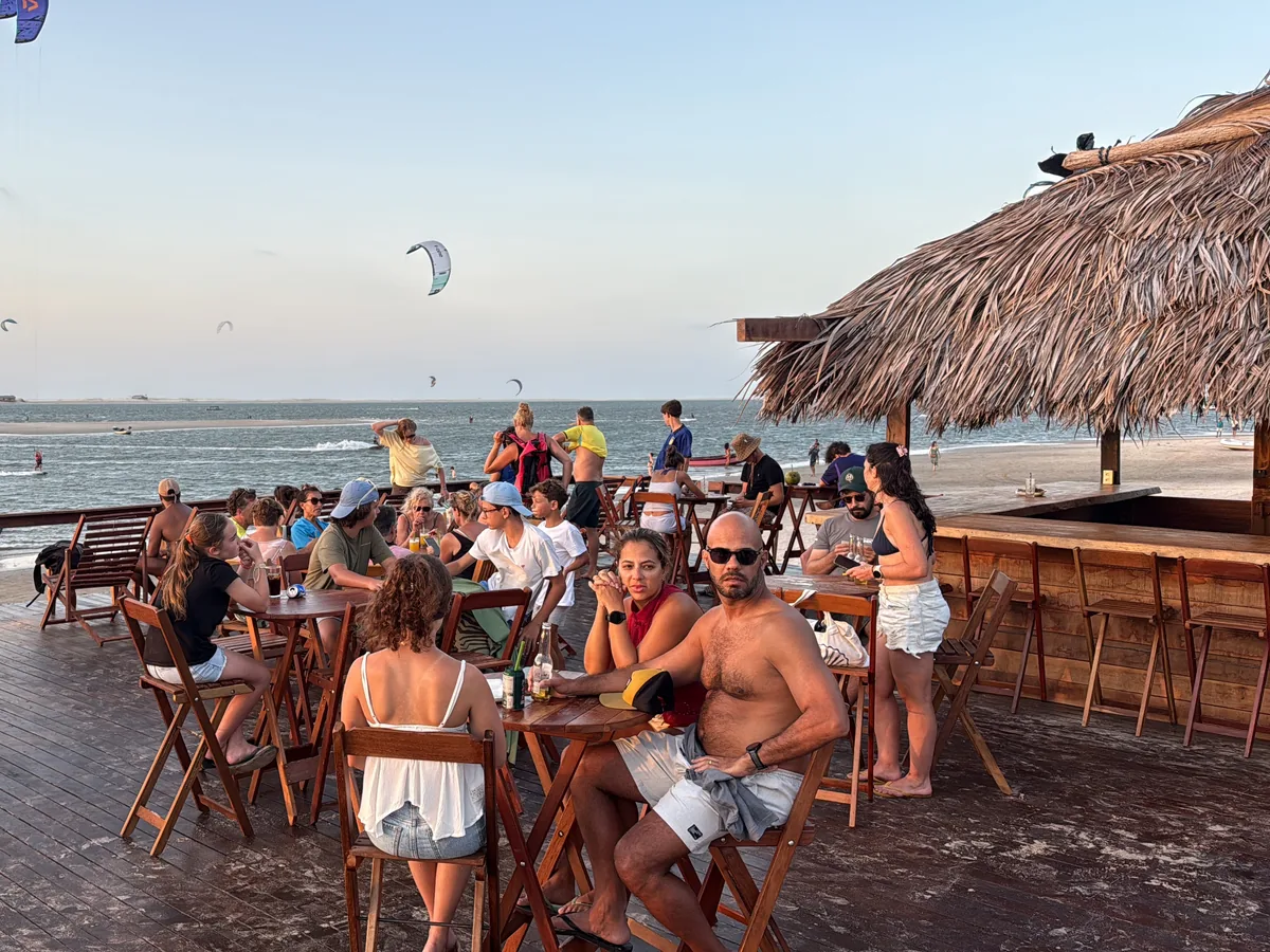 O Deck Beach Bar no fim de tarde, com o bar cheio e kitesurfistas no mar