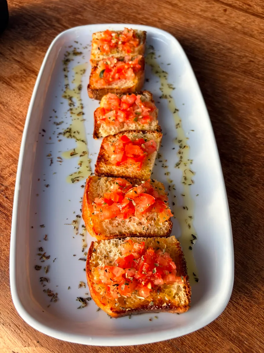 Tomato bruschetta with olive oil and oregano on a white platter