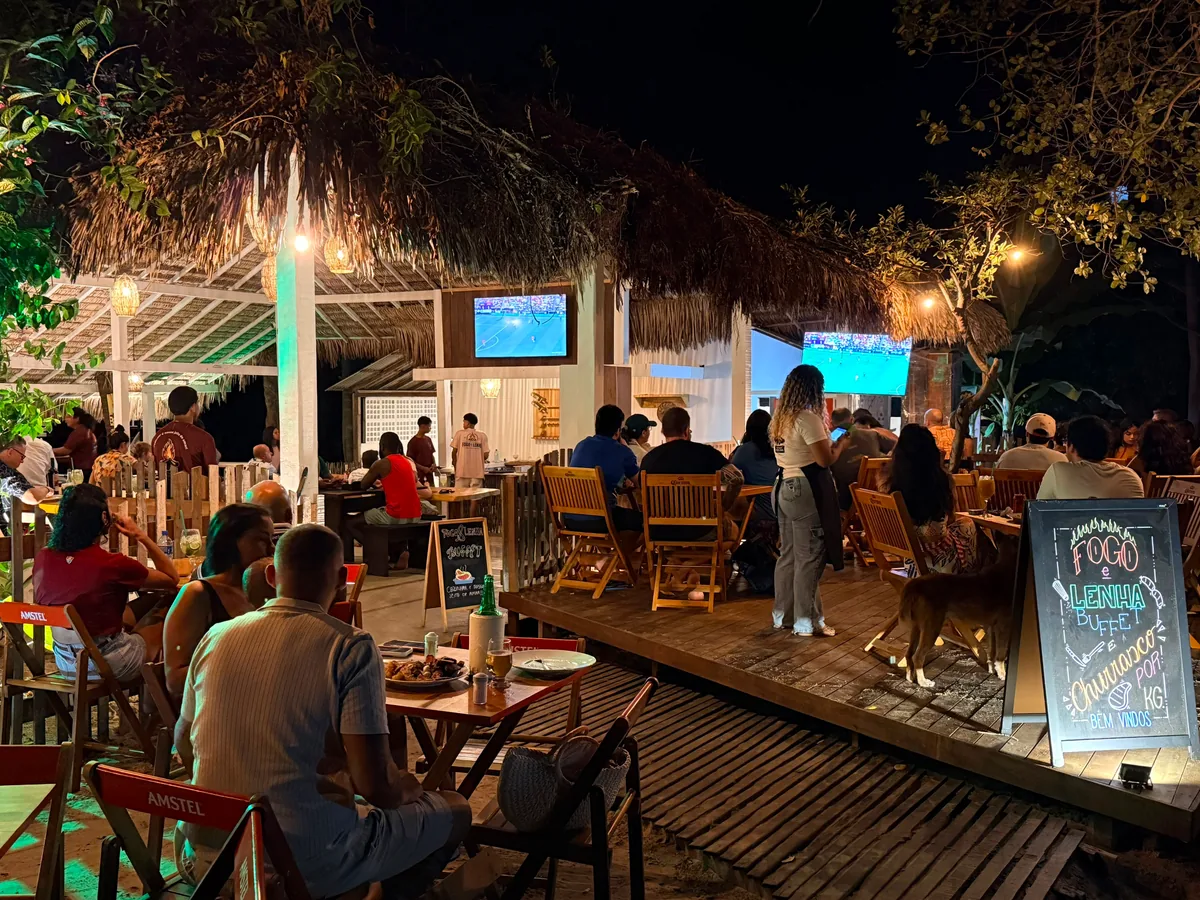 The Fogo e Lenha dining room at night, full of people, with the buffet and barbecue board