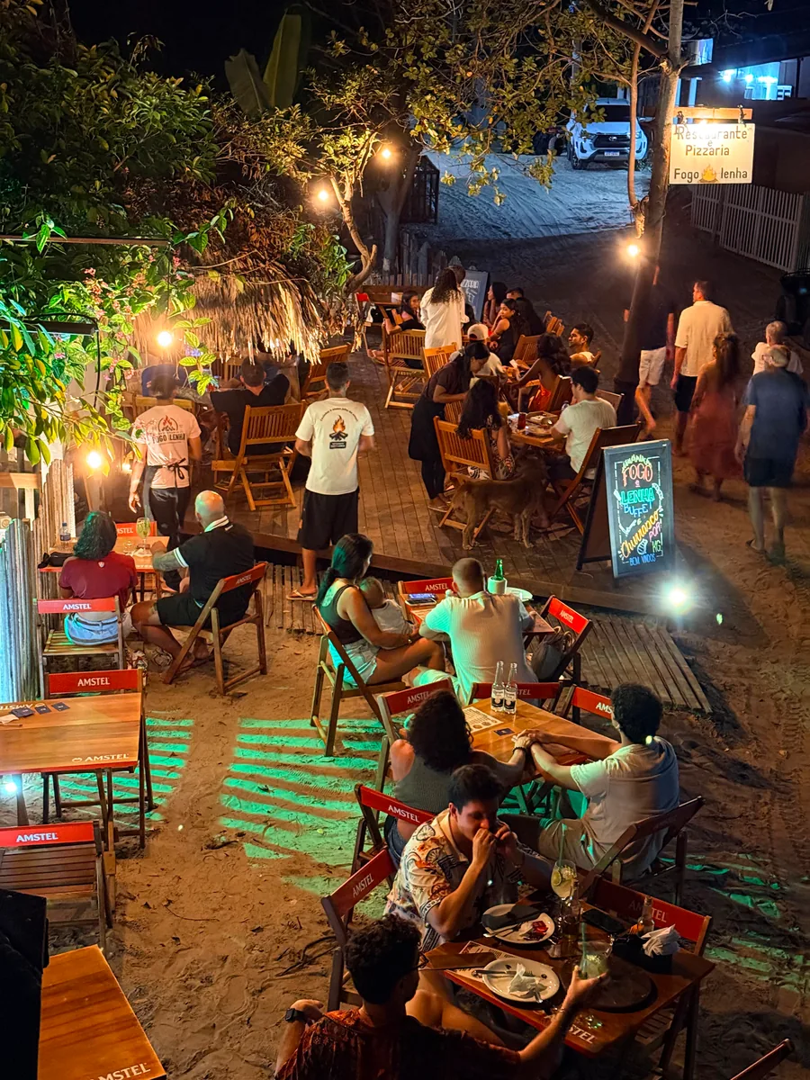 A fachada do Fogo e Lenha de frente para a praça de Atins, à noite