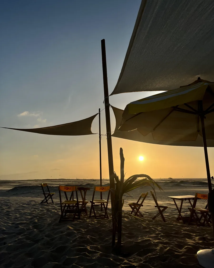 Tardo pomeriggio alla Cabana do Caranguejo: il sole basso dietro le vele ombreggianti e i tavoli sulla sabbia